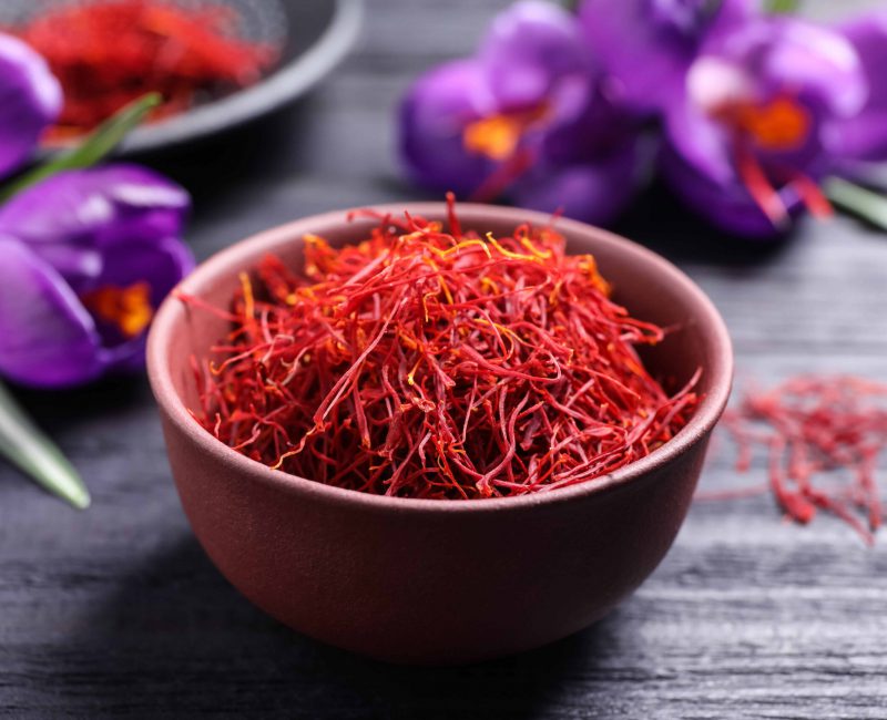 Dried,Saffron,In,Bowl,And,Crocus,Flowers,On,Black,Wooden